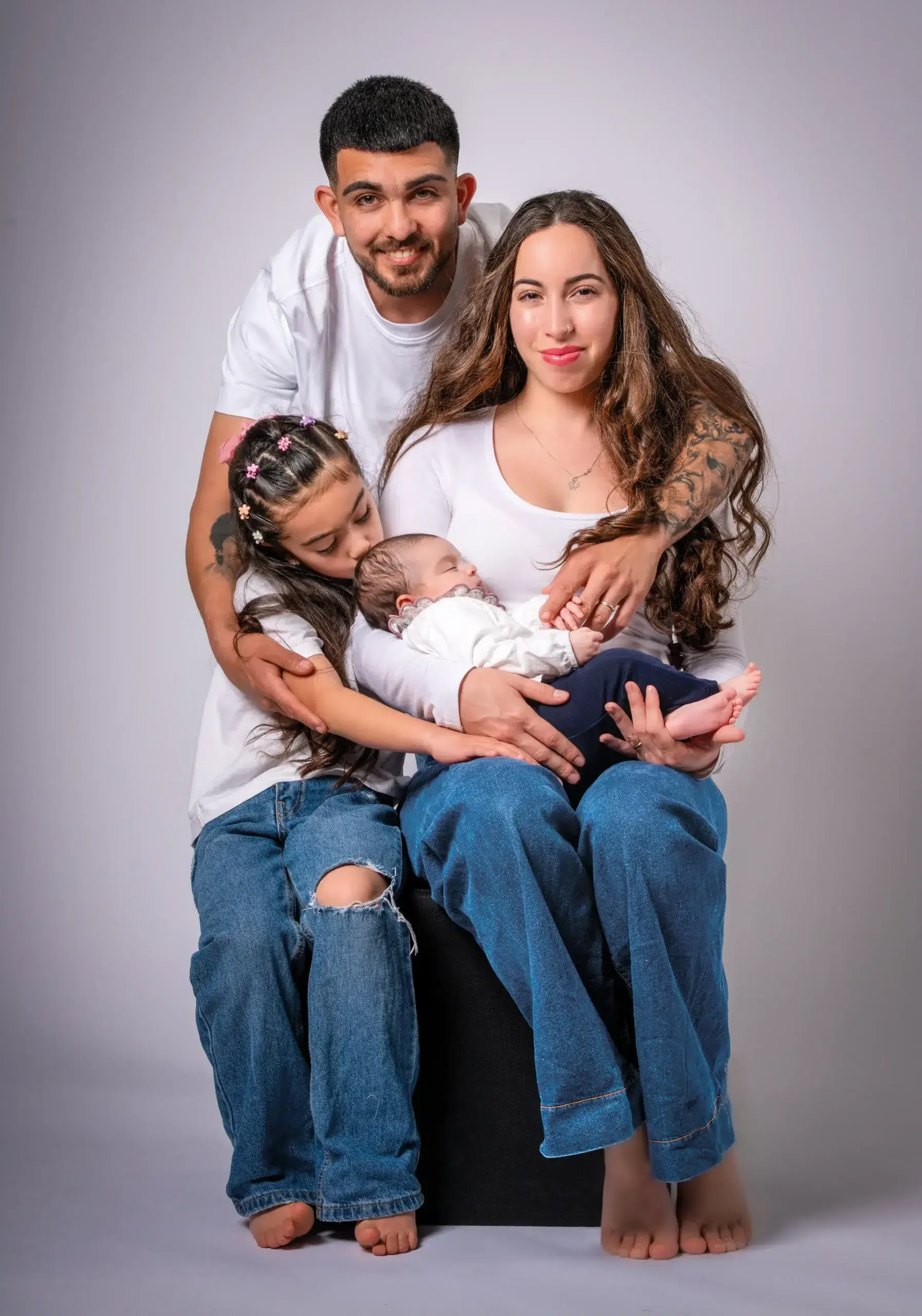 Padres y hermana mayor abrazando a un bebé recién nacido.